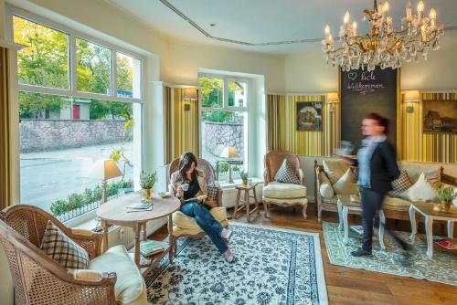 a woman sitting at a table in a living room at Hotel Wellness Goldenes Fass Meißen in Meißen