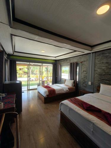 a hotel room with two beds and a window at Khao Sok Nung House in Khao Sok National Park