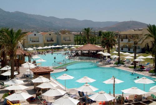 uma grande piscina com guarda-sóis brancos e pessoas nela em Zorbas Beach Hotel em Tigaki