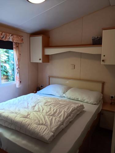 a bedroom with a large bed with white sheets at 't Kotje Ouddorp in Ouddorp