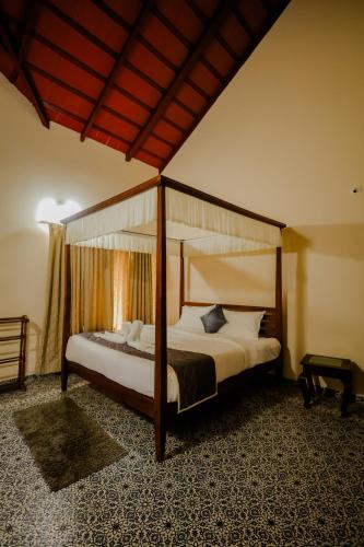 a bedroom with a four poster canopy bed at Akruthi Palm Pavilion Resort in Aldūr