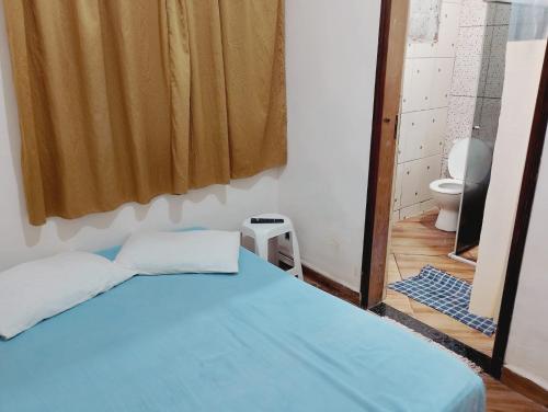 a bedroom with a blue bed and a toilet at quarto casal in Aparecida