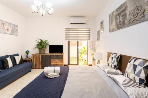 a living room with a blue couch and a tv at Malta Airport B&B bedroom with private shower