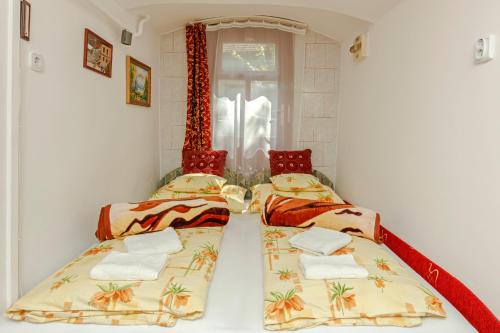 two beds in a small room with a window at Barokk Vendégház in Eger