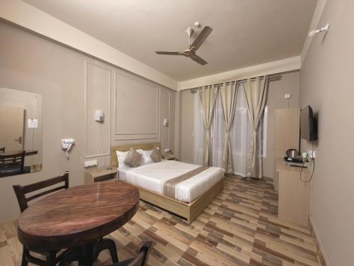 a bedroom with a bed and a table and a ceiling fan at Restel Guest House in Guwahati