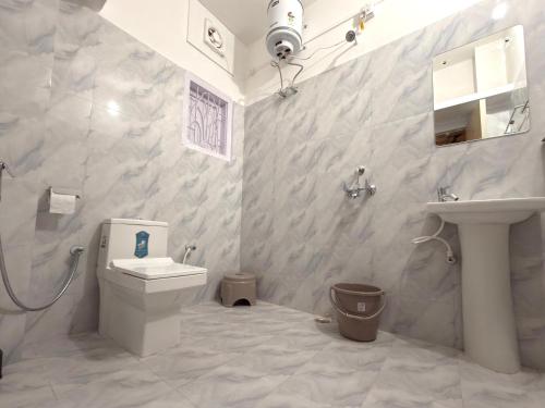 a white bathroom with a toilet and a sink at Restel Guest House in Guwahati