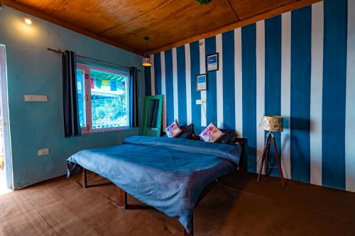 a bedroom with a bed with blue and white stripes at Backpacker Storey in Bīr