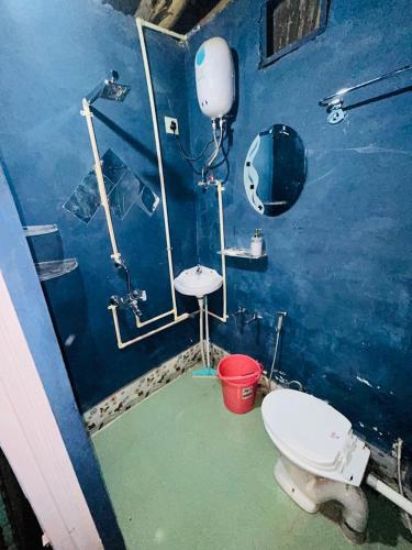 a blue bathroom with a toilet and a sink at Backpacker Storey in Bīr