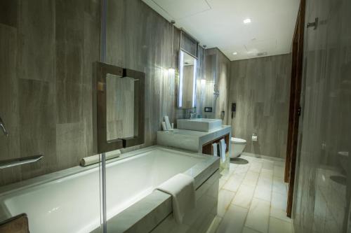 ein Badezimmer mit einer Badewanne, einem Waschbecken und einem WC in der Unterkunft Winford Resort and Casino Manila in Manila