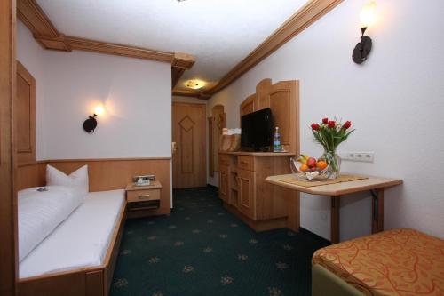 a hotel room with a bed and a desk with a television at Alphotel Garni Salner in Ischgl