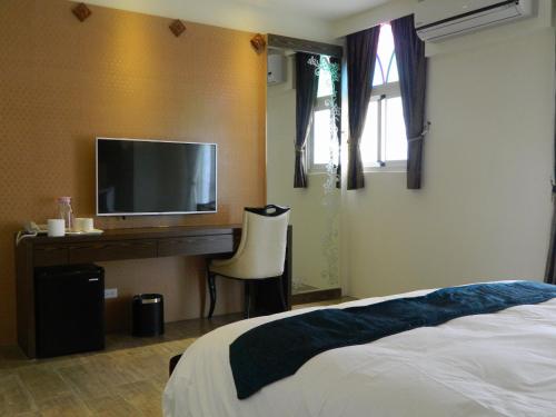 a bedroom with a bed and a desk with a television at Dream Ocean View B&B in Magong
