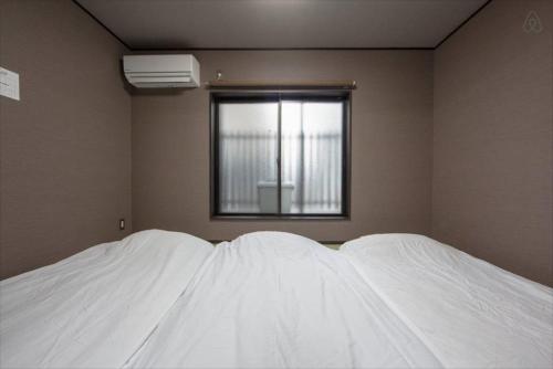 two white beds in a room with a window at Imagine Annex in Kyoto