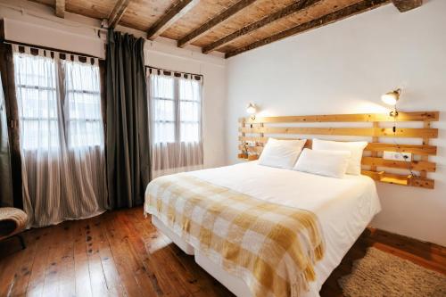 a bedroom with a large white bed and two windows at El rinconin del Sueve in San Martín
