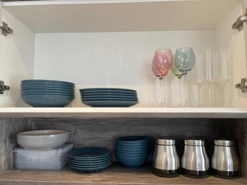 a shelf with plates and wine glasses on it at Exclusive 1 and 2 Bedroom Flats only 0,5 miles aw in Bicester