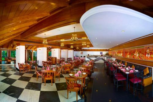 a restaurant with tables and chairs and a checkered floor at The Mascot Hotel - A Heritage Living Experience in Trivandrum