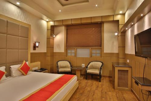 a hotel room with a bed and a television at Hotel The Grand Chandiram in Kota