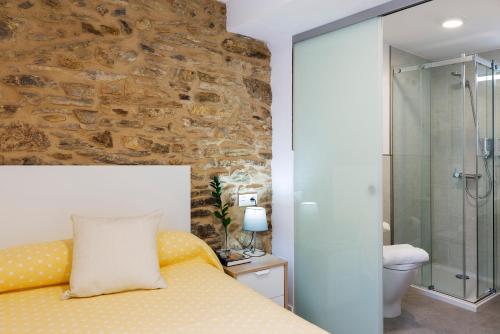 a bedroom with a bed and a stone wall at Pensión Rua Nova in Santiago de Compostela