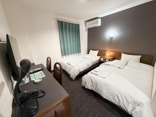 a hotel room with two beds and a desk at Hotel Tetora HonHachinohe in Hachinohe