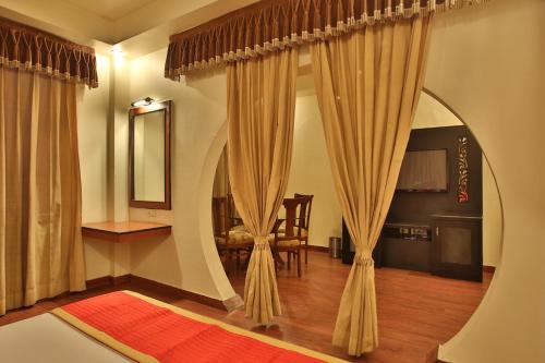 a room with curtains and a table and a mirror at Hotel The Grand Chandiram in Kota