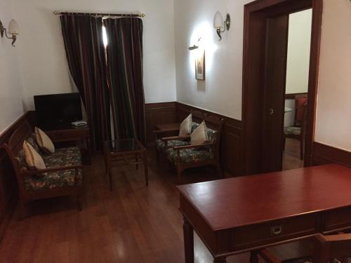 a living room with chairs and a table and a mirror at The Mascot Hotel - A Heritage Living Experience in Trivandrum