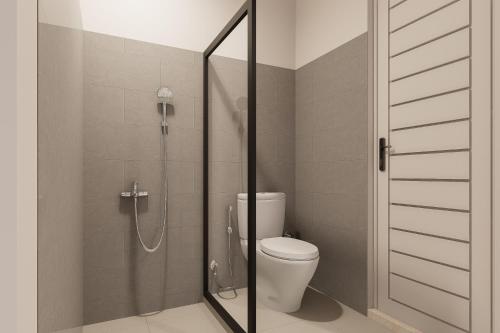 a bathroom with a toilet and a glass shower stall at Mecutan Guest House in Jimbaran