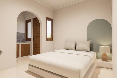 a white bedroom with a bed and a bathroom at Mecutan Guest House in Jimbaran