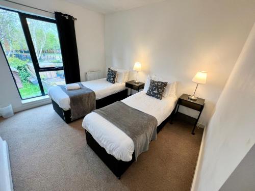 a hotel room with two beds and a window at Spacious 5 bed townhouse Manchester, Salford Qauys - Two Bedroom with Parking in Manchester