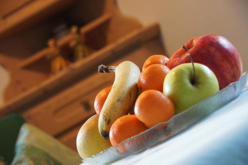 a bowl of fruit on a counter with apples and oranges at Ciasa Complojer in La Valle