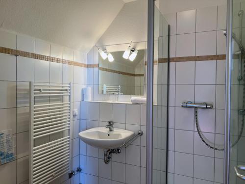 a bathroom with a sink and a glass shower at Zeitlos Hotel Garni in Scharbeutz