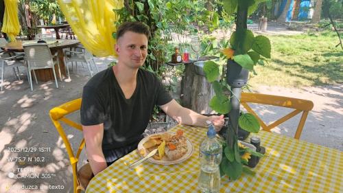 a man sitting at a table with a plate of food at Coco Encantado Eco Hostal Camping in Cartagena de Indias
