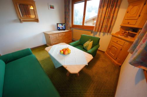a living room with a table and green chairs at Ciasa Complojer in La Valle