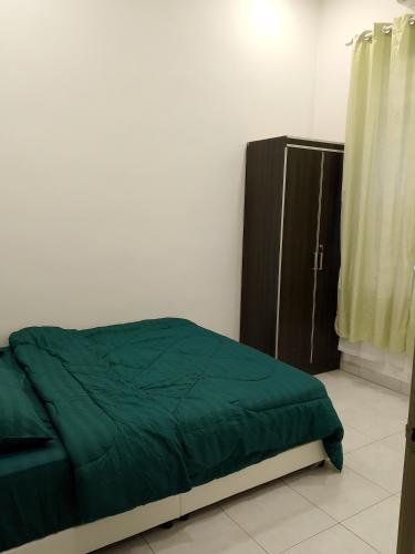 a bedroom with a green bed and a cabinet at NJAZ Homestay Perlis in Arau