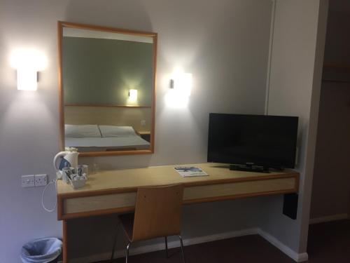 a room with a desk with a computer and a mirror at Redwings Lodge Rutland in Uppingham