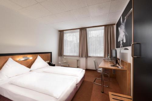 a hotel room with a bed and a desk and window at Days Inn Dortmund West in Dortmund