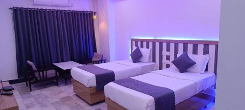 a hotel room with two beds and a table and chairs at HoTEL JAGAPATHI INTERNATIONAL in Vijayawāda