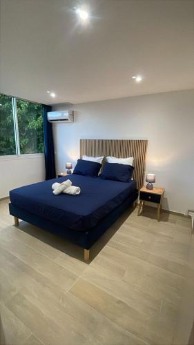 a bedroom with a bed with blue sheets and blue pillows at L'Aparté des hibiscus in Les Trois-Îlets