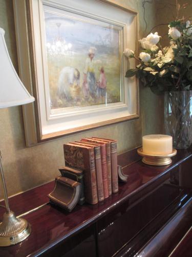 a table with books and a painting and a lamp at Drumhierney Lodge in Leitrim