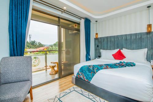 a bedroom with a bed and a chair and a balcony at Hotel La vena in Kampala