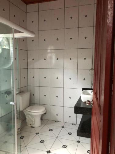a bathroom with a toilet and a tiled wall at Pousada Pineiro in Paraty