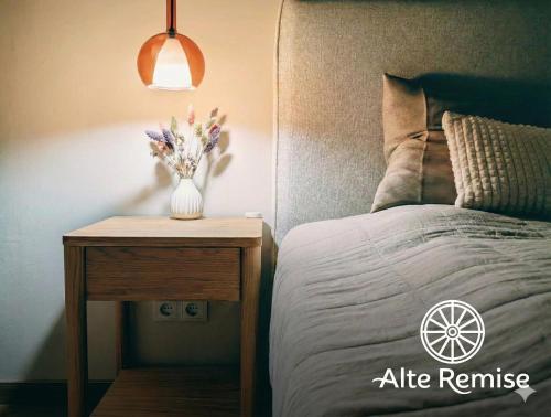 a bed with a table with a vase of flowers on it at Alte Remise Blankenburg in Blankenburg