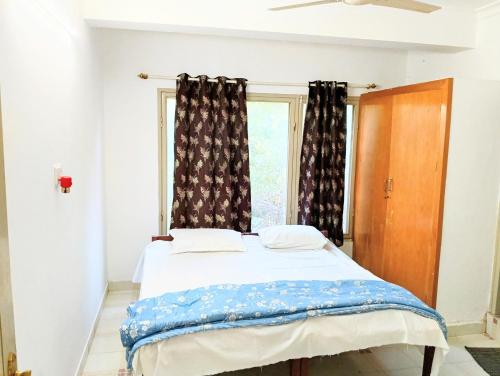a bed in a room with a window at Chetanya Homestay in Puttaparthi