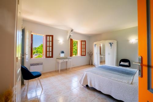 a bedroom with a bed and a desk and windows at La Ferme des Grisettes in Montesquiou
