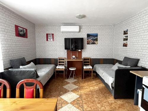 a living room with two beds and a tv at Tabán Apartman in Dunakeszi