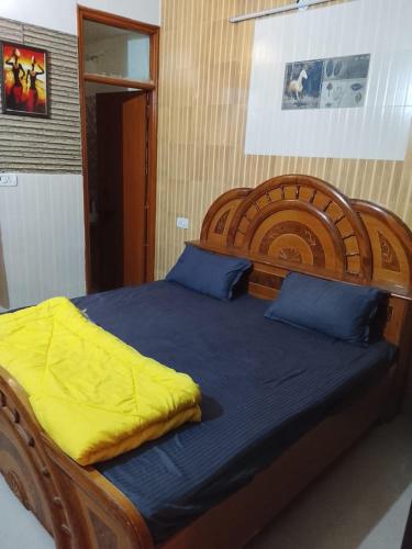 a large bed with a wooden headboard and blue sheets at Esadan in Agra