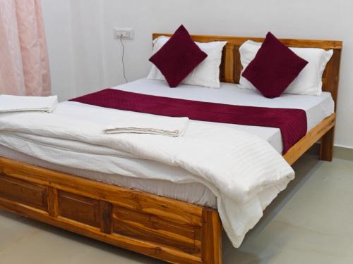 a bedroom with a large bed with red and white pillows at Bellevue Retreat in Alībāg