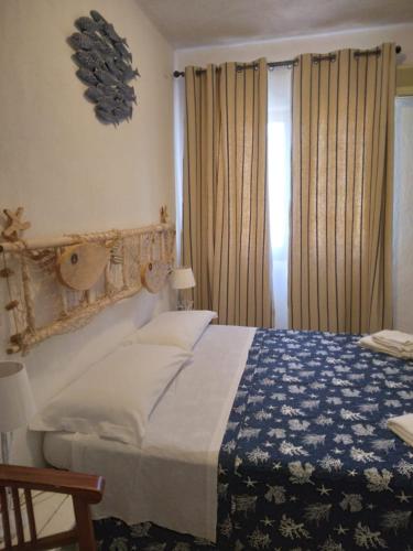a bedroom with a bed with a blue and white blanket at La Dea Madre in Stintino