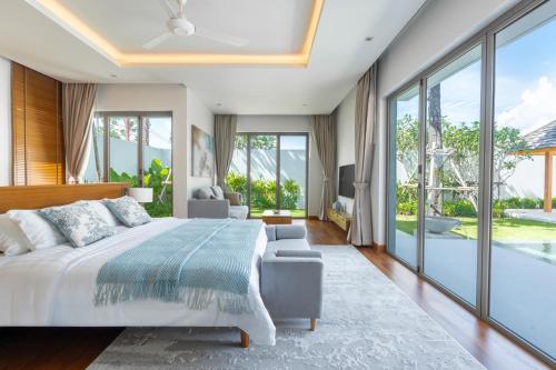 a bedroom with a bed and a large window at Anchan Flora by Villacarte in Ban Phru Champa