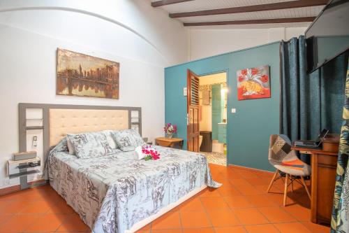 a bedroom with a bed and a desk in it at Alpinia-Martinique, à 5 minutes de la plage in Sainte-Anne