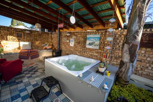 a bath tub in a patio with a brick wall at Windsong Living - Eagle Owl in Krugersdorp