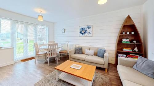 a living room with a couch and a table at Life of Filey - Part of the The Bay Filey Holiday Village with pool, gym and direct beach access, pub, restaurant, tennis and meadows walks in Reighton